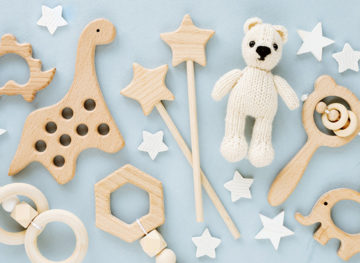 Cute wooden baby toys on light-blue background